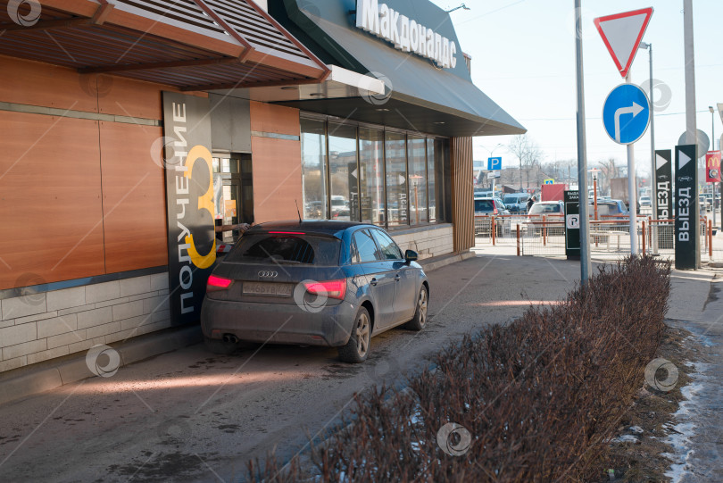 Скачать Пункт обслуживания водителей в ресторане McDonald's. Мужчина в машине, покупающий еду навынос в McDrive. Смоленск, Россия 04.12.2021 фотосток Ozero