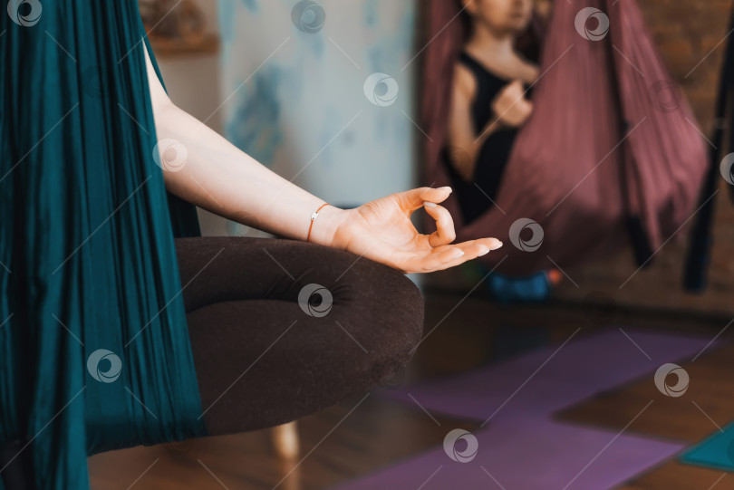 Скачать Женщина, практикующая антигравитационную йогу в гамаке в помещении. Крупный план женской руки в позе медитации. Сосредоточьтесь на руке фотосток Ozero