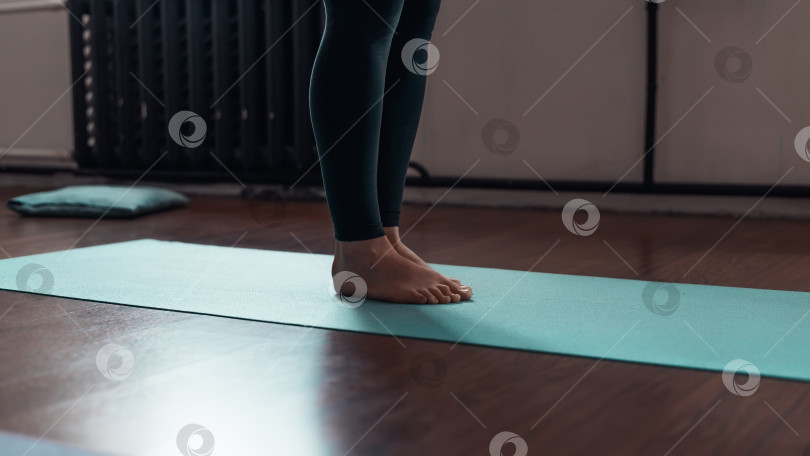 Скачать Женщина, стоящая на коврике для йоги в классе, крупным планом. Обрезка, выборочный фокус фотосток Ozero