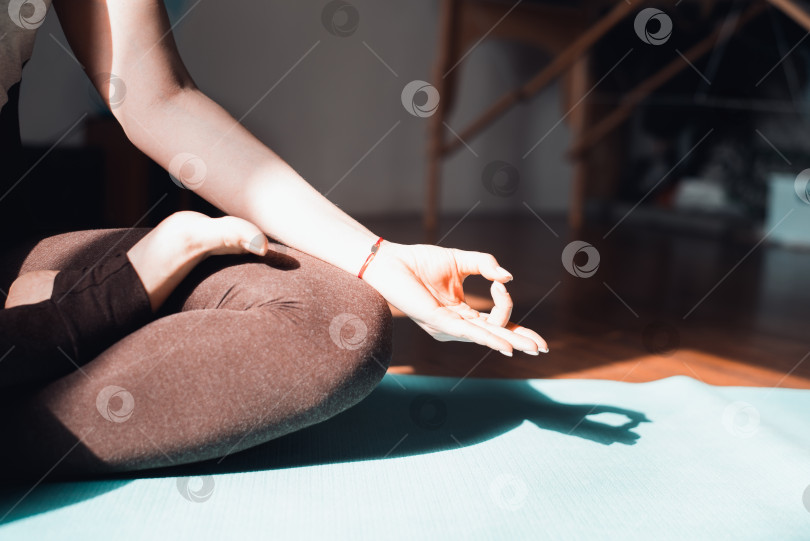 Скачать Крупным планом рука молодой женщины, практикующей медитацию, сидя в позе лотоса на коврике для йоги, в помещении на рассвете. Концепция медитации осознанности, здорового образа жизни. Избирательный фокус фотосток Ozero