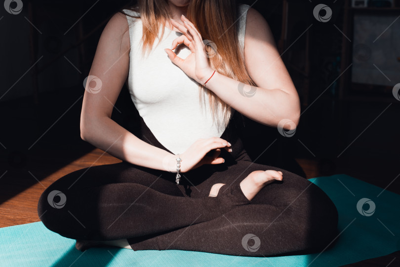 Скачать Молодая женщина, практикующая медитацию на коврике для йоги в помещении, крупным планом. Руки сложены в асане. Концепция осознанной медитации, релаксации, здорового образа жизни фотосток Ozero