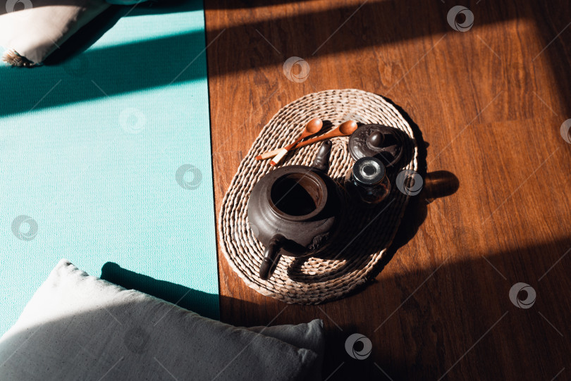 Скачать Церемония травяного чая на закате в комнате для медитации. Глиняный чайник и деревянные ложки на коврике, вид сверху. Концепция гармонии, расслабления фотосток Ozero