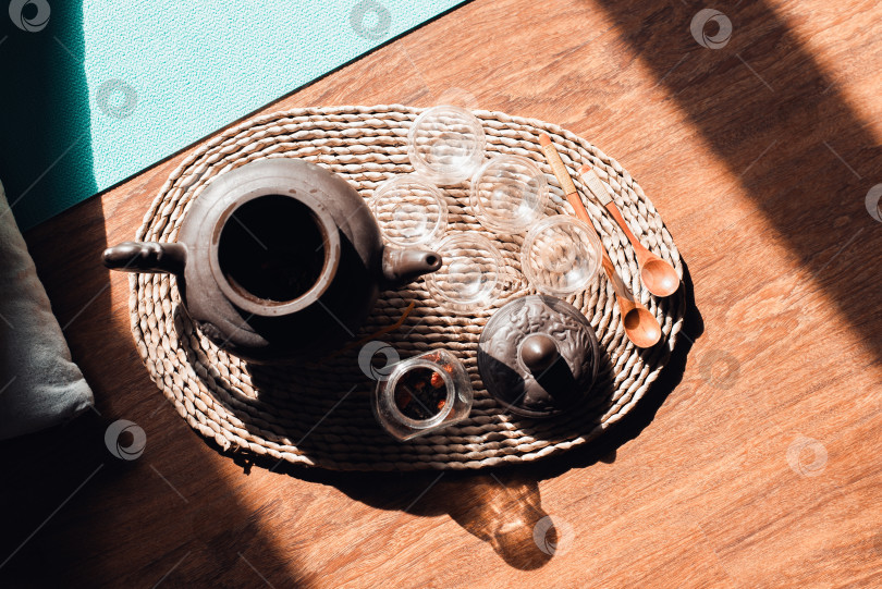 Скачать Утренняя чайная церемония в зале для медитаций. Глиняный чайник, стеклянные чашки и деревянные ложки на подносе, вид сверху. Концепция гармонии, расслабления фотосток Ozero