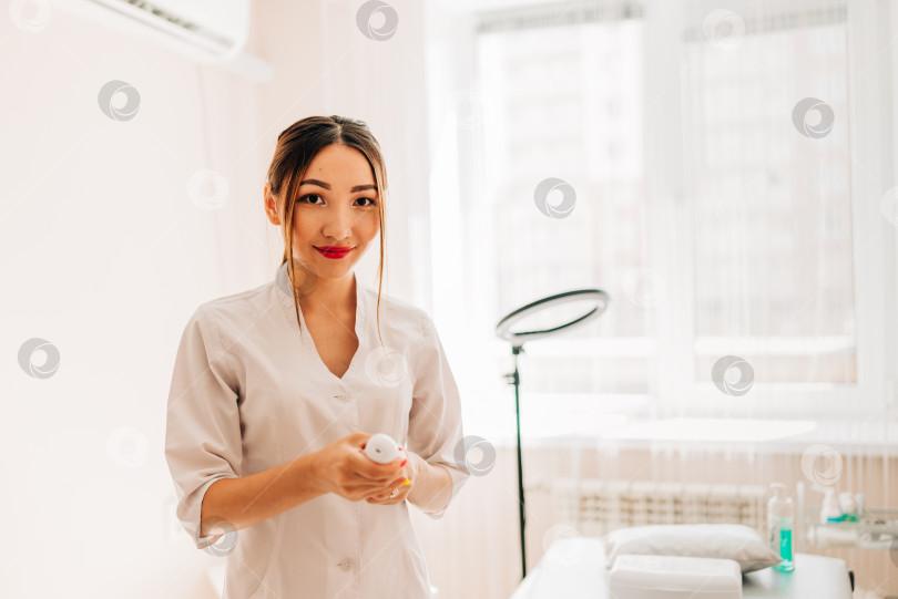 Скачать Молодая улыбающаяся женщина-врач-косметолог в белой форменной одежде фотосток Ozero