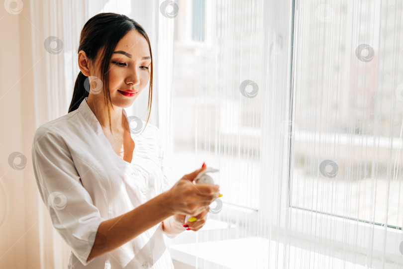 Скачать Молодая улыбающаяся женщина-врач-косметолог в белой форменной одежде фотосток Ozero