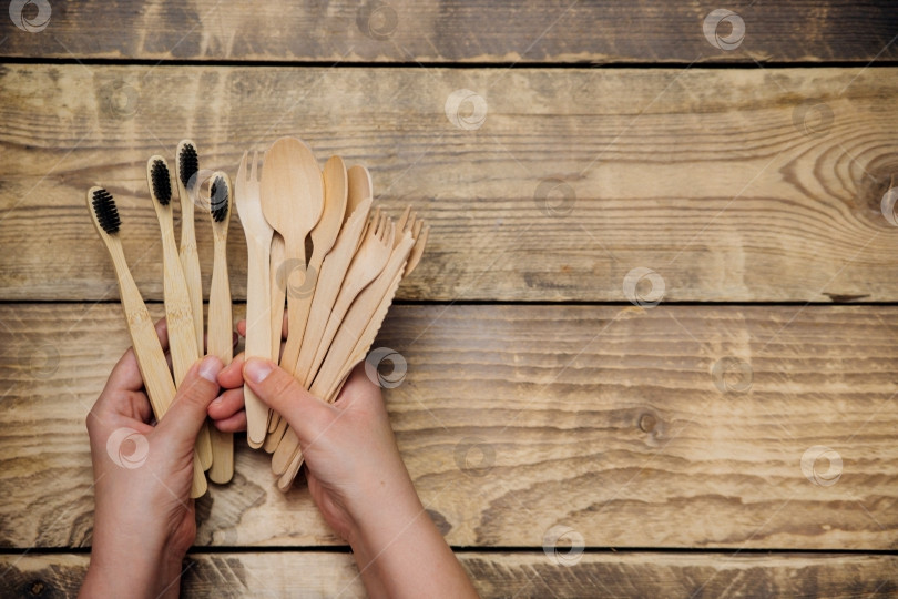 Скачать Женские руки держат деревянные бамбуковые ложки, ножи, вилки и зубные щетки. Концепция нулевых отходов без пластика. фотосток Ozero