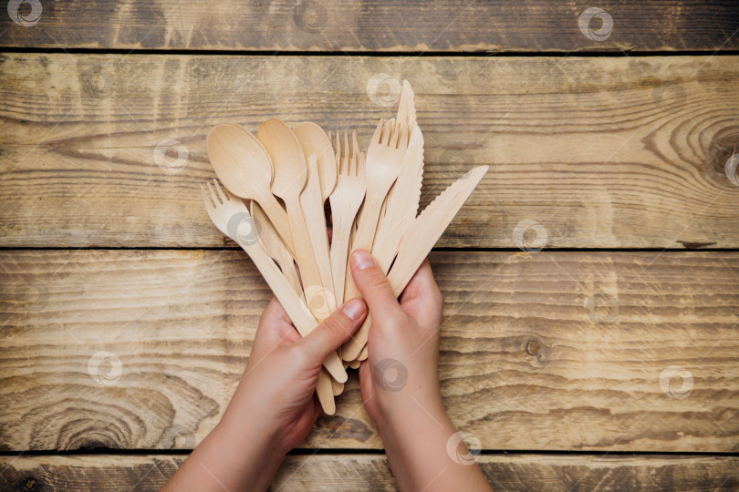 Скачать Женские руки держат деревянные бамбуковые ложки, ножи и вилки. Концепция нулевых отходов без пластика. фотосток Ozero