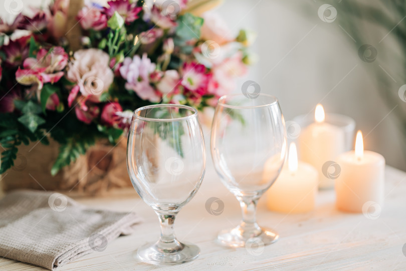 Скачать Праздничный ужин. Праздничная сервировка стола с цветами и свечами. Красивый столик с бокалами для напитков и уютными огоньками пламени. Детали романтического вечера фотосток Ozero