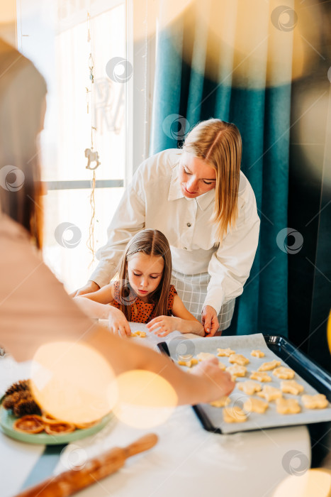 Скачать Счастливые мать и дочь готовят на кухне, дочь смеется и наслаждается семейным приготовлением домашнего печенья. Солнечный день дома в закрытом помещении фотосток Ozero