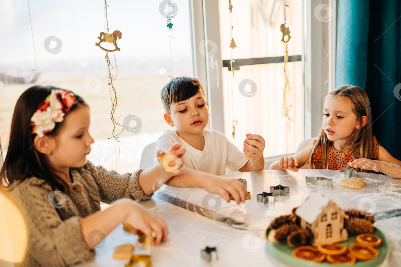 Скачать Счастливые дети вместе готовят пекарню с печеньем и весело проводят время с мукой в помещении уютного дома на кухонном столе. Братья и сестры в большой любящей семье фотосток Ozero