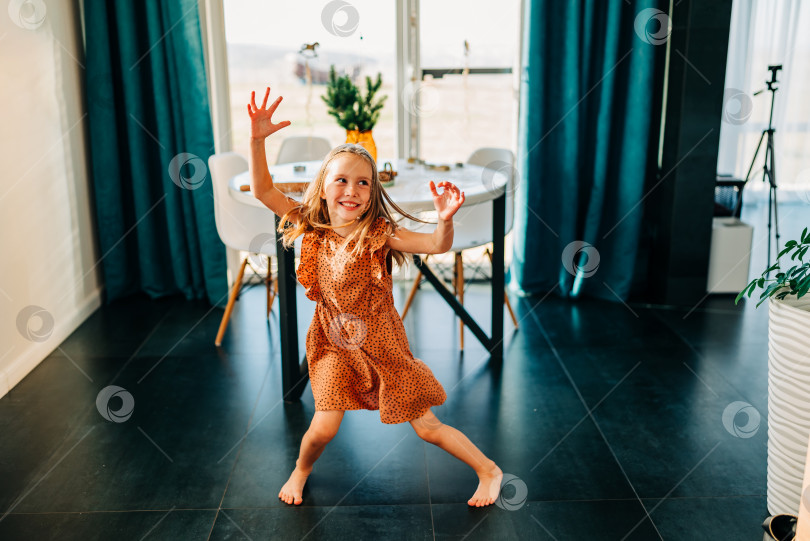 Скачать Забавный очаровательный счастливый ребенок девочка прыгает дома в помещении, милый маленький ребенок весело танцует под музыку, играющую в помещении в одиночестве наслаждайтесь притворяясь танцором утром фотосток Ozero