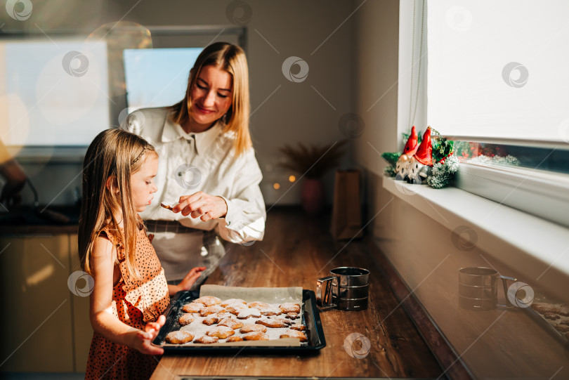 Скачать Счастливые мать и дочь готовят на кухне, дочь смеется и наслаждается семейным приготовлением домашнего печенья. Солнечный день дома фотосток Ozero