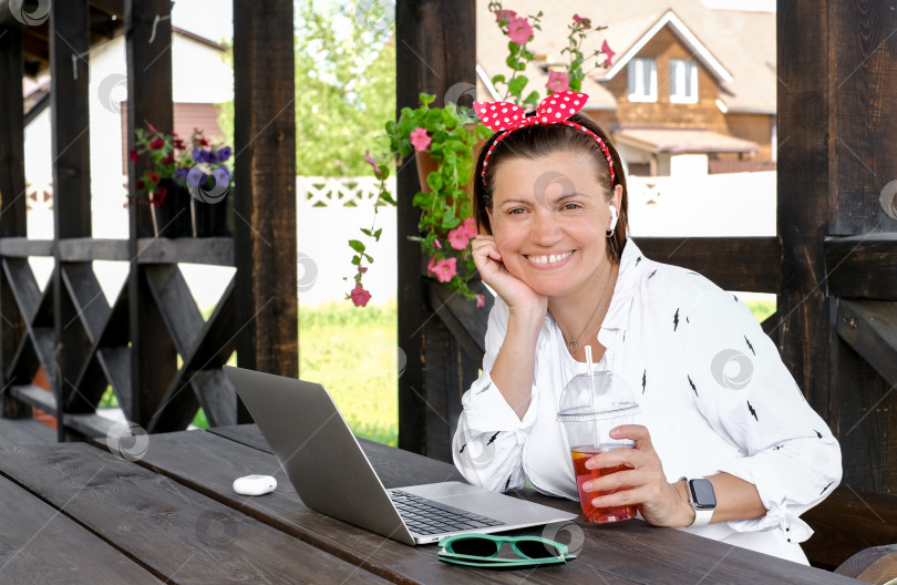 Скачать Концепция фрилансера. Симпатичная женщина пользуется ноутбуком на открытой террасе кафе. Работайте и путешествуйте жарким летом фотосток Ozero
