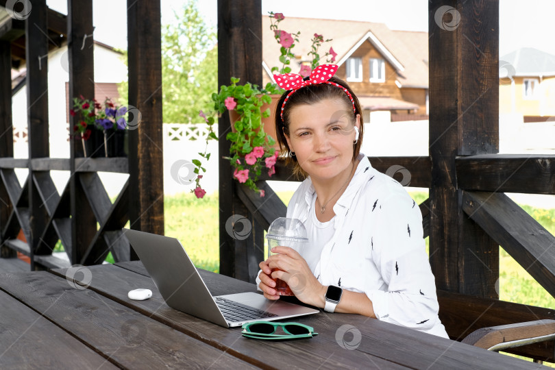Скачать Концепция фрилансера. Симпатичная женщина пользуется ноутбуком на открытой террасе кафе. Работа и путешествия жарким летом фотосток Ozero
