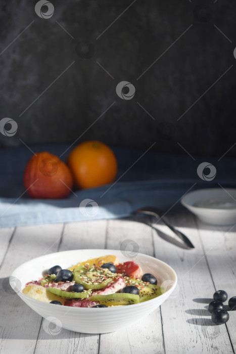 Скачать фото натюрморт, тарелка с фруктовым салатом, ягодами черники, ложкой и йогуртом, деревенский фотосток Ozero