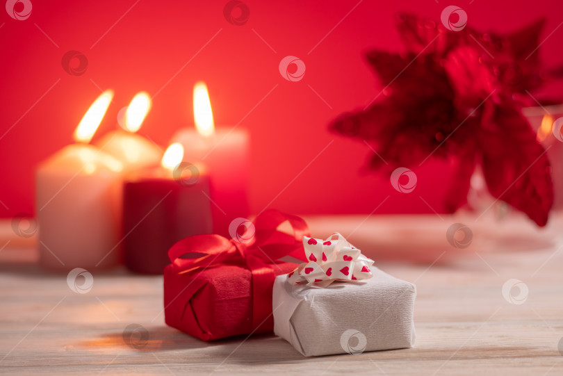 Скачать Две подарочные коробки на столе со свечами, украшающими празднование дня святого Валентина на красном фоне фотосток Ozero
