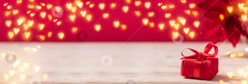 Скачать Баннер с красной подарочной коробкой на столе с сердечками, гирляндой в стиле боке, копировальным пространством для празднования дня святого Валентина фотосток Ozero