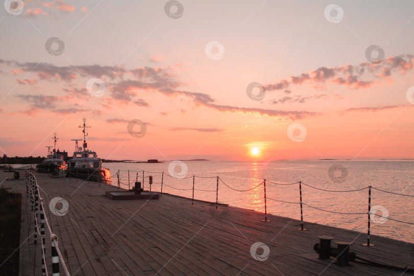 Скачать Лодки у старого деревянного пирса с видом на море и розовый закат. фотосток Ozero