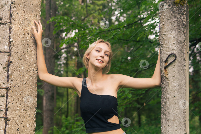 Скачать улыбающаяся молодая женщина позирует рядом с бетонными сваями среди природных фотосток Ozero