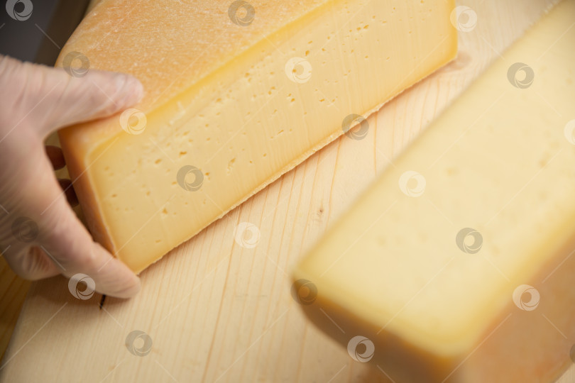 Скачать сыр разных сортов на натуральном деревянном фоне, цельный и нарезанный фотосток Ozero