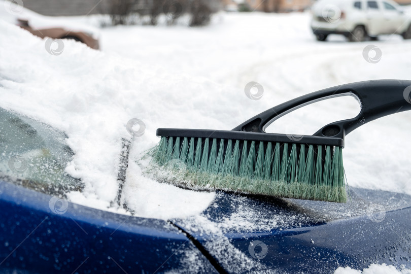 Скачать Капот автомобиля чистят щеткой после снегопада фотосток Ozero