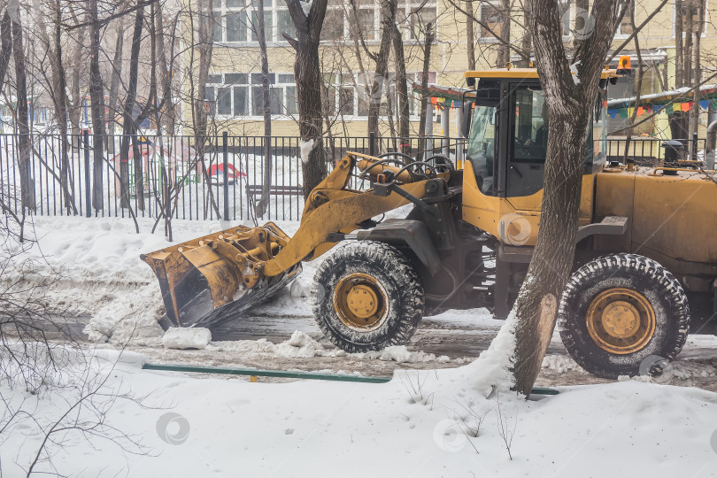 Скачать трактор расчищает снег с улицы во дворе фотосток Ozero