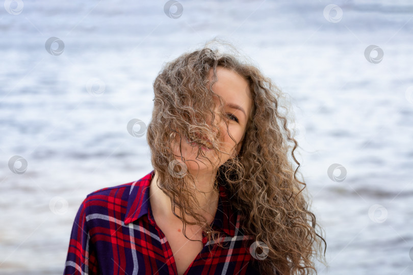 Скачать женщина с вьющимися волосами в одиночестве прогуливается по берегу реки на ветру, фотосток Ozero