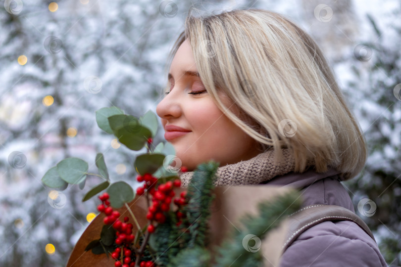 Скачать Одинокая молодая женщина наслаждается рождественским букетом в заснеженном зимнем парке. Любовь к себе, одиночество в шуме фотосток Ozero