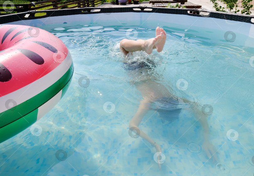 Скачать Мальчик-подросток находится в бассейне с игрушечным кольцом и маской. Концепция летнего отдыха. фотосток Ozero