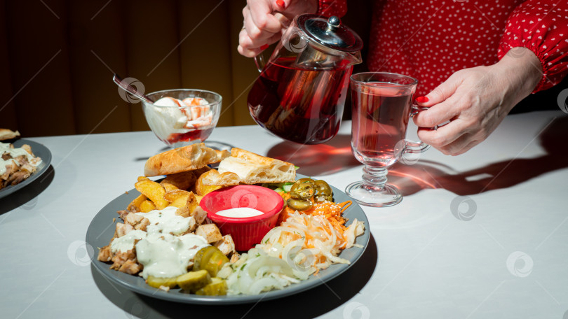 Скачать Куриная шаверма на тарелке с лепёшкой, картофелем фри, капустой, луком, солеными огурцами, морковью и майонезным соусом. Вид сбоку фотосток Ozero