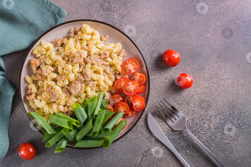 Скачать Макароны с мясным фаршем, помидорами и зеленым луком на тарелке на фотосток Ozero