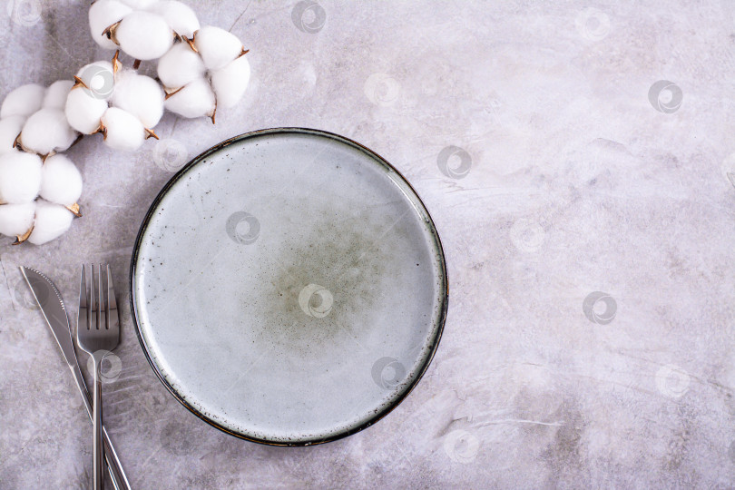 Скачать Пустая керамическая тарелка, столовые приборы и хлопчатобумажная ветка на сером фоне фотосток Ozero