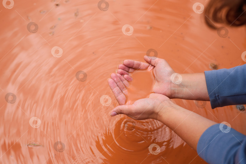 Скачать Женщина зачерпывает пригоршню красной жидкости. Изменение расхода воды фотосток Ozero