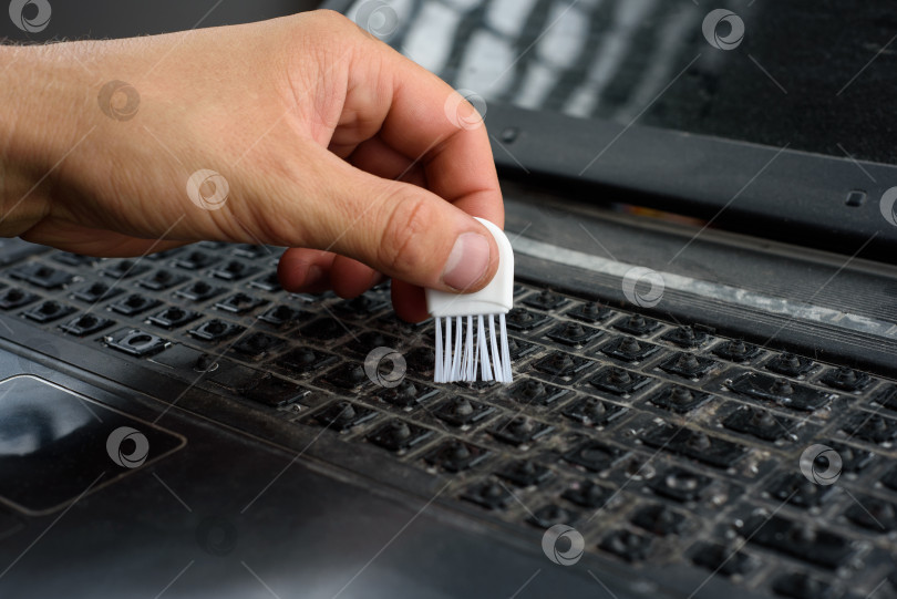Скачать Мужская рука чистит щеткой грязную клавиатуру без клавиш фотосток Ozero