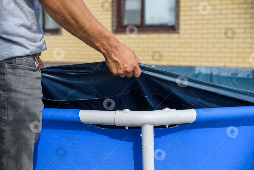 Скачать Мужчина натягивает покрывало на домашний плавательный бассейн. Защита от мусора фотосток Ozero