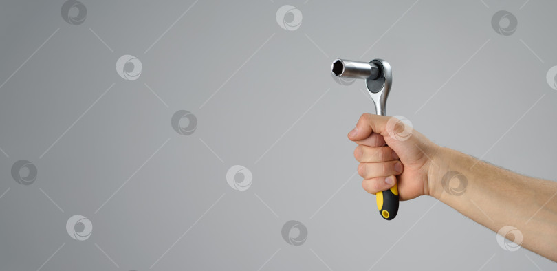 Скачать Мужская рука держит торцевой ключ с храповиком, чтобы что-то починить. Сделай это фотосток Ozero