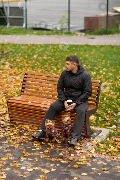 Скачать Мужчина сидит на скамейке в парке с чашкой кофе, два фотосток Ozero