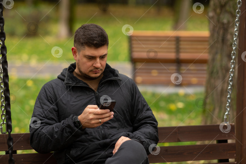 Скачать Мужчина сидит осенью на скамейке в парке, наблюдая за фотосток Ozero