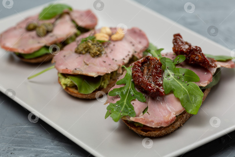 Скачать Ассорти из трех брускетт с мясом индейки, авокадо, помидорами фотосток Ozero