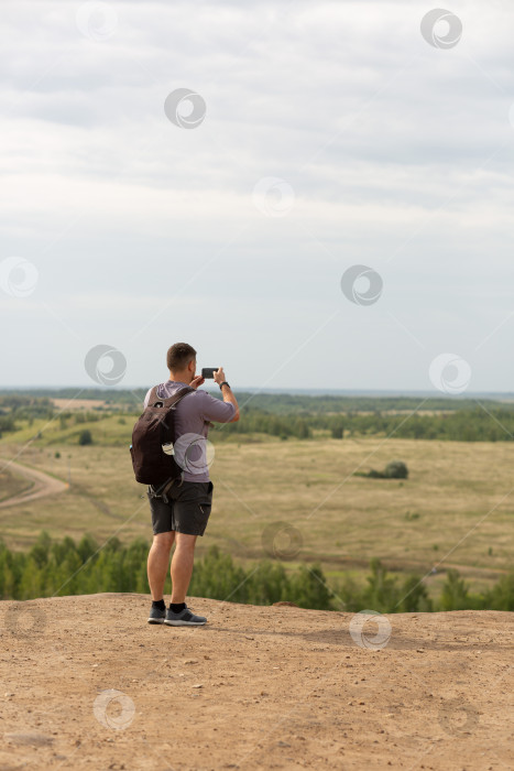 Скачать Мужчина стоит на холме и фотографирует вид со своего фото фотосток Ozero