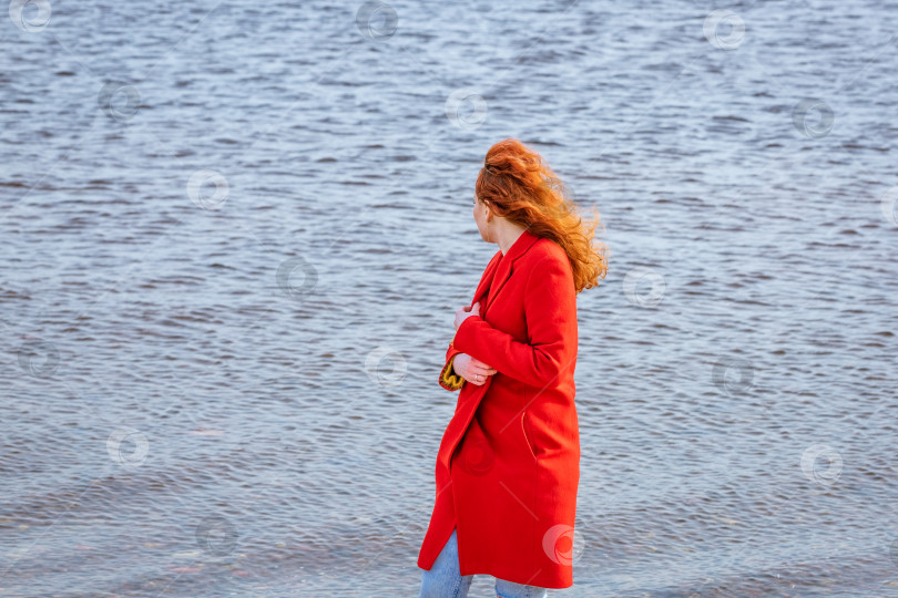 Скачать Привлекательная рыжеволосая женщина прогуливается по улице в городе рядом с рекой, выходные на свежем воздухе фотосток Ozero