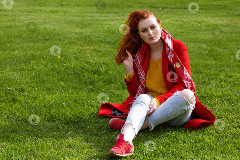 Скачать одинокая женщина в красном пальто сидит на зеленой траве фотосток Ozero