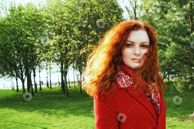 Скачать Портрет симпатичной женщины в красном пальто на фоне зеленого парка фотосток Ozero