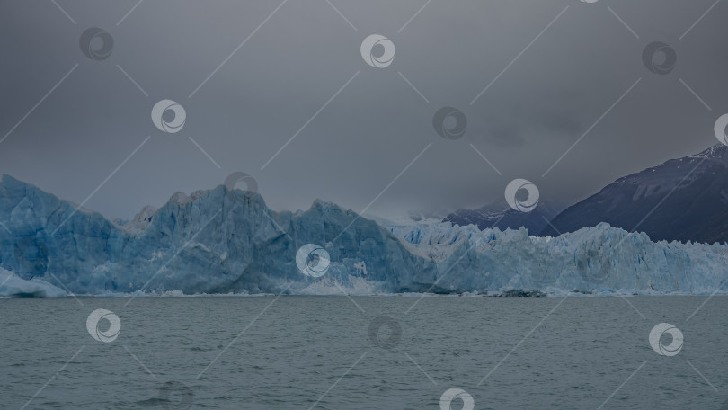 Скачать Ледник Перито-Морено. Стена из потрескавшегося голубого льда возвышается над бирюзовым озером. фотосток Ozero