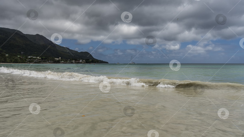 Скачать Волна бирюзового океана накатывает на берег, извиваясь и смешиваясь с песком пляжа. фотосток Ozero