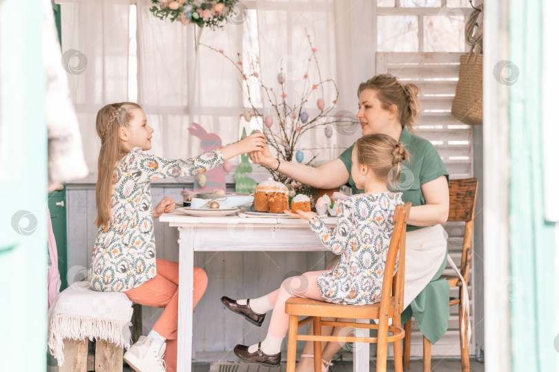 Скачать время пасхальных каникул в весенний сезон. счастливая семья откровенные маленькие дети сестры девочки вместе с мамой весело проводят время дома, украшая стол к обеду или ужину. традиционная еда. праздничный домашний декор фотосток Ozero