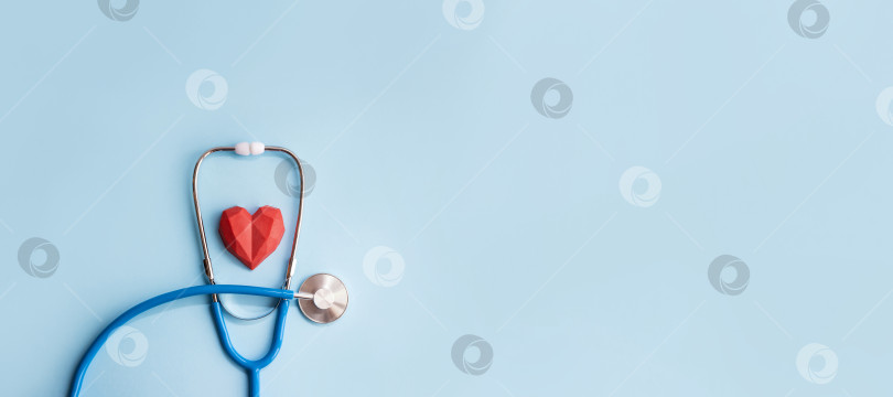 Скачать Медицинский стеноскоп и красное многоугольное сердце на синем фоне. фотосток Ozero