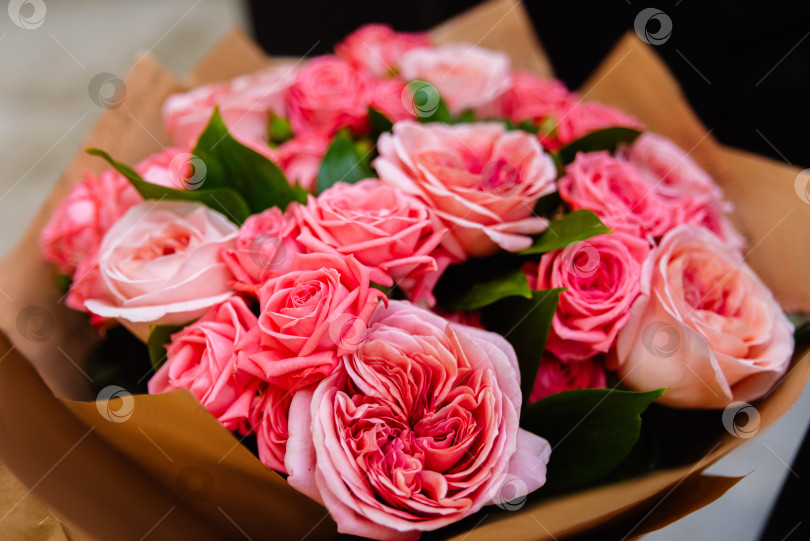 Скачать Букет розовых роз в обертке из крафт-бумаги на темном фоне фотосток Ozero