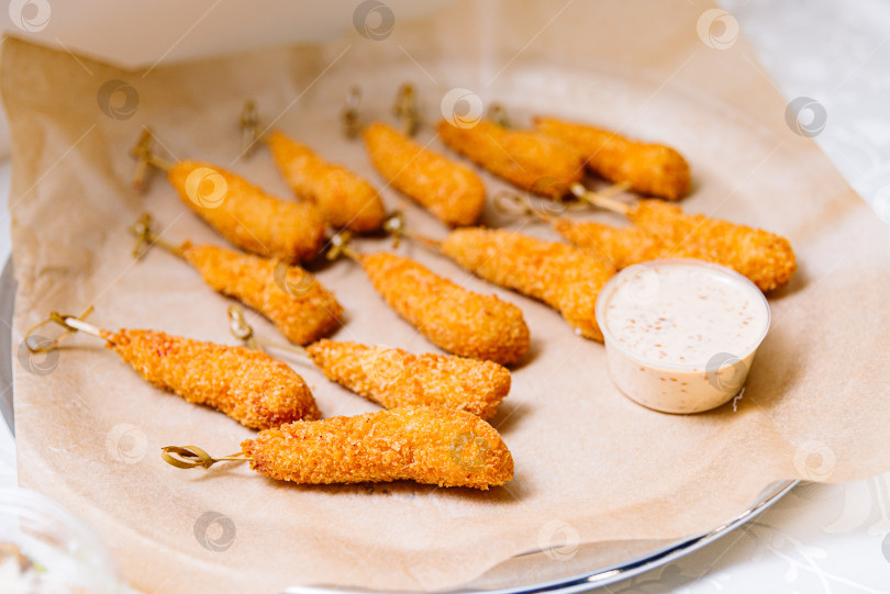 Скачать Жареные куриные наггетсы на шпажках со сливочным соусом на тарелке фотосток Ozero