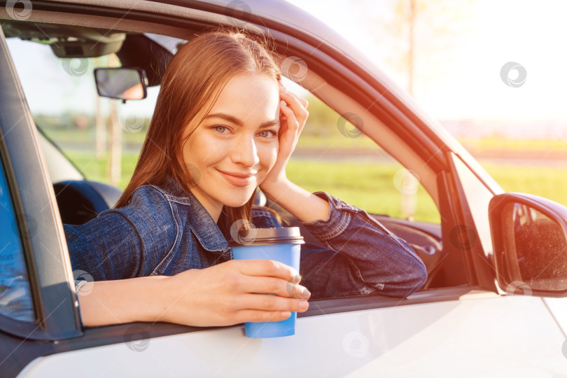 Скачать Красивая молодая женщина ехала по дороге в автомобиле, попивая кофе из одноразовой фотосток Ozero